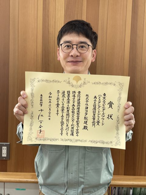 東京エコビルダーズアワードの賞状を持つ、株式会社ヨコタ総建の社長